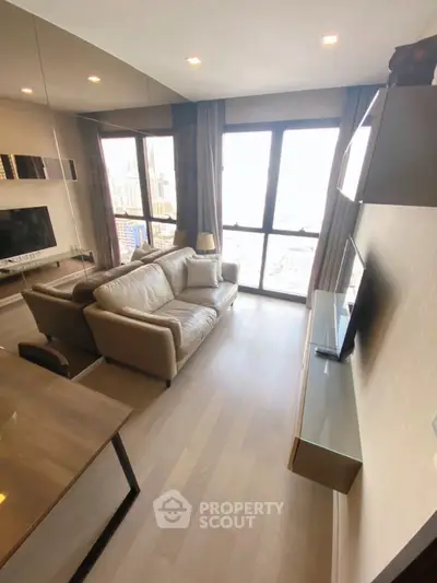 Modern living room with large windows and city view, featuring a cozy sofa and wall-mounted TV.