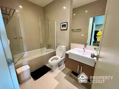 Modern bathroom with sleek fixtures and glass shower partition in a stylish apartment.