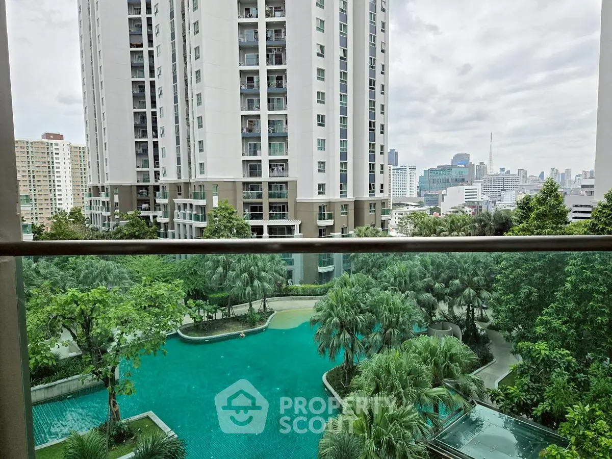 Stunning city view from balcony overlooking lush garden and pool in modern high-rise building.