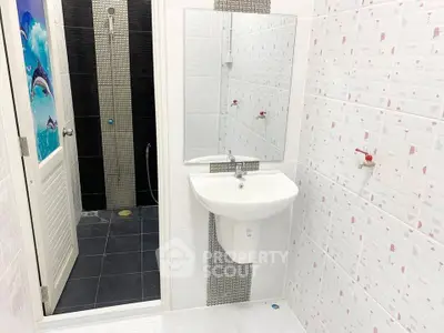Modern bathroom with sleek sink and shower area featuring stylish tiles.