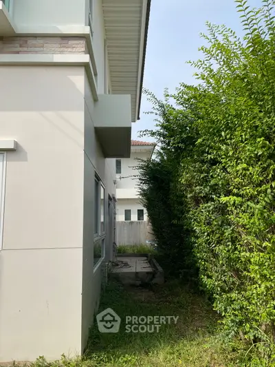 Modern residential building exterior with lush greenery and clear sky.