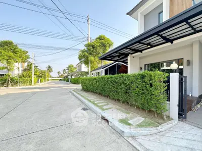 Modern suburban house with lush greenery and spacious driveway in a tranquil neighborhood.