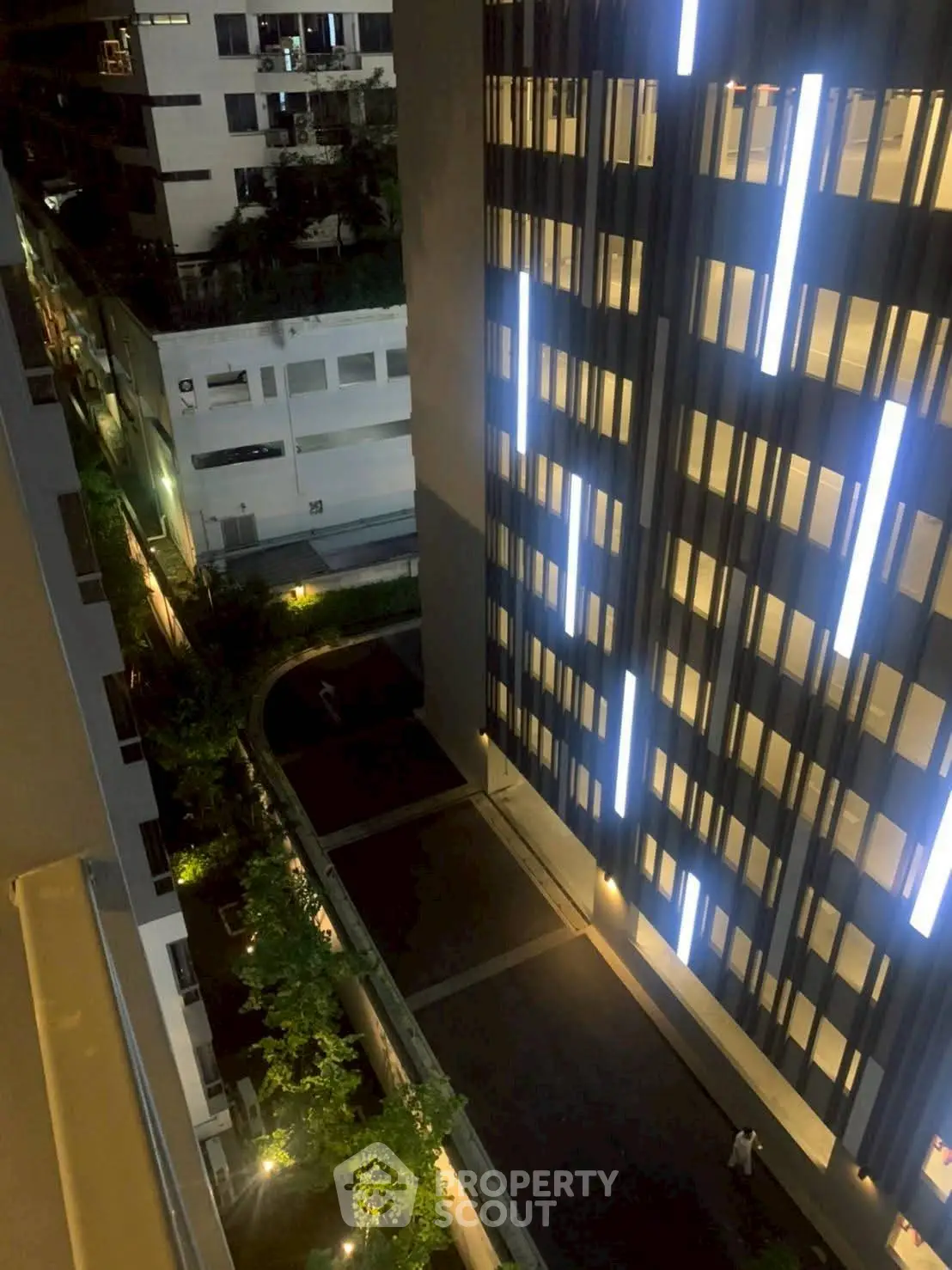 Stunning night view of modern building with illuminated facade and surrounding greenery.