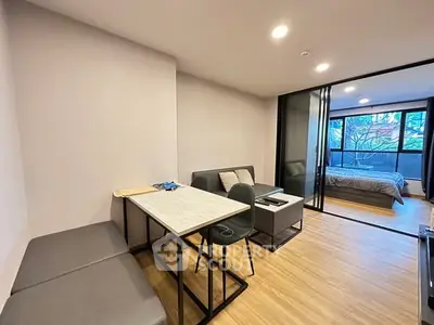 Modern apartment with open living and bedroom space, featuring sleek furniture and large windows.