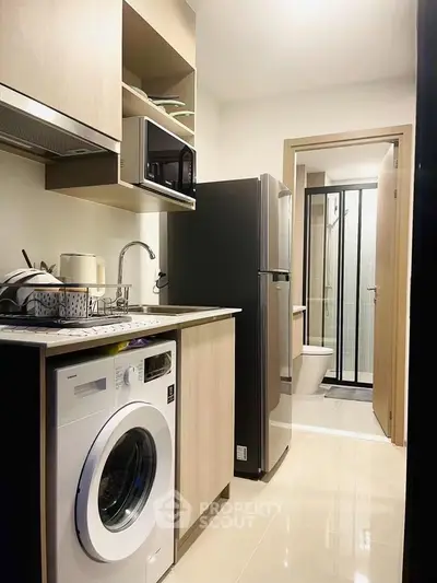 Compact kitchen with modern appliances and adjacent bathroom in a cozy apartment.