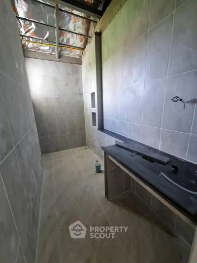 Modern bathroom under construction with tiled walls and floor