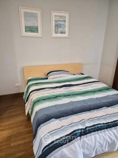 Cozy bedroom with modern decor and wooden flooring, perfect for relaxation.