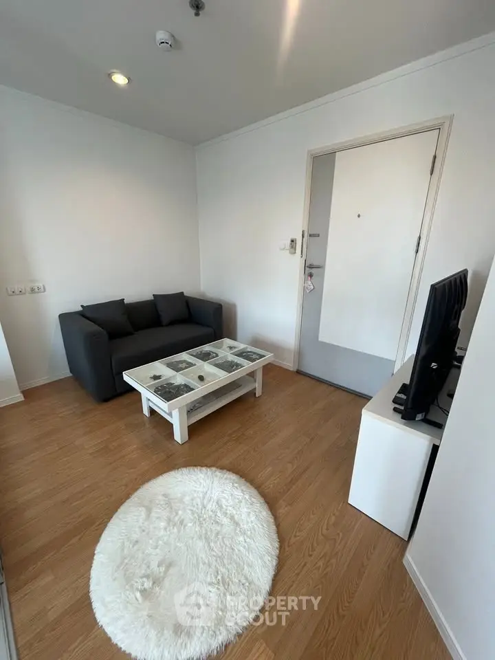 Cozy living room with modern decor, featuring a sleek sofa, stylish coffee table, and wooden flooring.