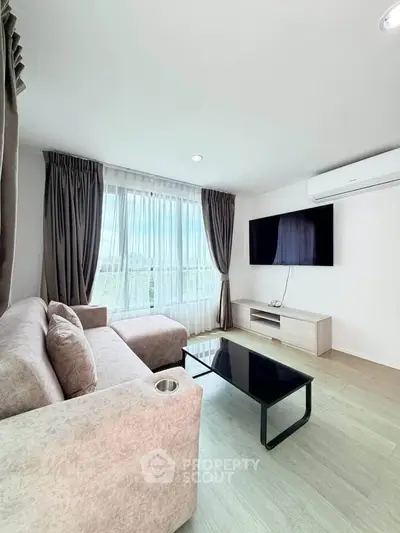 Modern living room with large window, stylish sofa, and wall-mounted TV in a bright apartment.