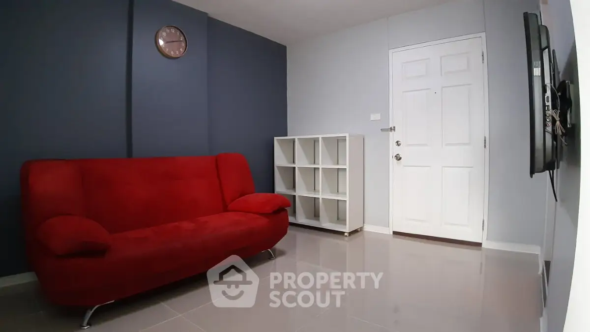 Modern living room with red sofa and sleek white shelving unit.