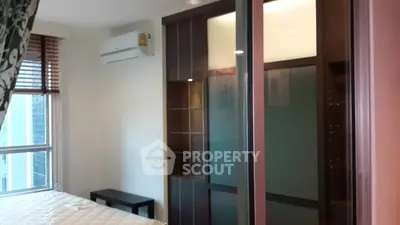 Modern bedroom with large window and sleek wardrobe in a high-rise apartment.