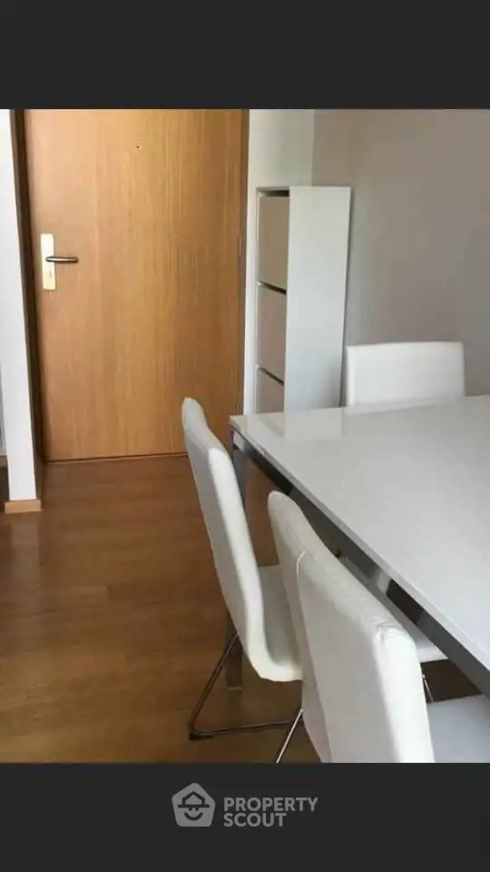 Modern dining area with sleek white chairs and wooden flooring, perfect for contemporary living.