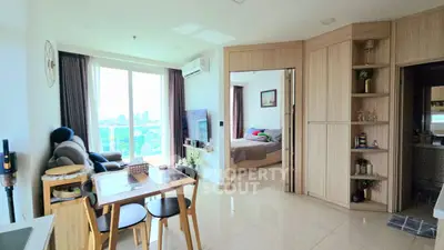 Modern open-plan living room with dining area and bedroom, featuring large windows and stylish decor.