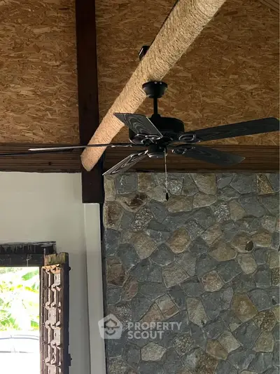 Rustic interior with stone wall and ceiling fan in cozy living space
