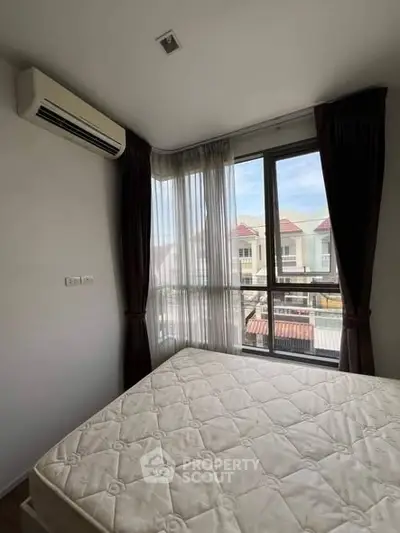Bright bedroom with large windows and air conditioning unit, offering a cozy and comfortable living space.