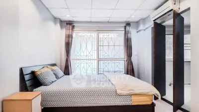 Cozy bedroom with modern decor and large window, perfect for relaxation and comfort.