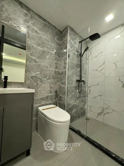Modern bathroom with sleek design, featuring a glass shower and elegant marble tiles.