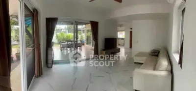 Spacious living room with modern decor and large windows opening to a lush garden view.