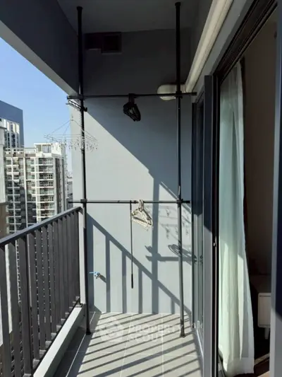 Modern balcony with city view and hanging racks in a high-rise apartment.