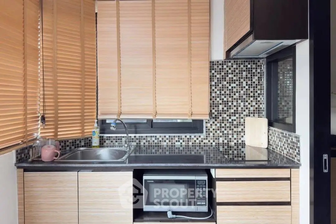 Modern kitchen with sleek cabinetry, mosaic backsplash, and built-in microwave for stylish urban living.