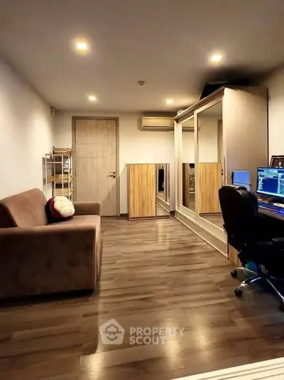 Spacious study room with modern decor and wooden flooring, featuring a comfortable sofa and work desk.