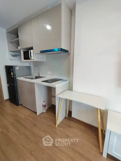 Modern compact kitchen with sleek cabinets and built-in appliances in a stylish apartment.