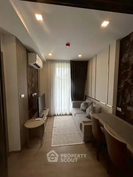 Modern living room with stylish decor and natural light, featuring a cozy sofa and sleek TV setup.