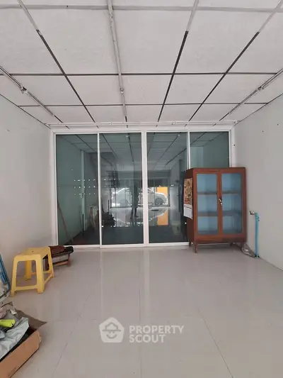 Spacious commercial space with glass partition and tiled flooring, ideal for retail or office setup.