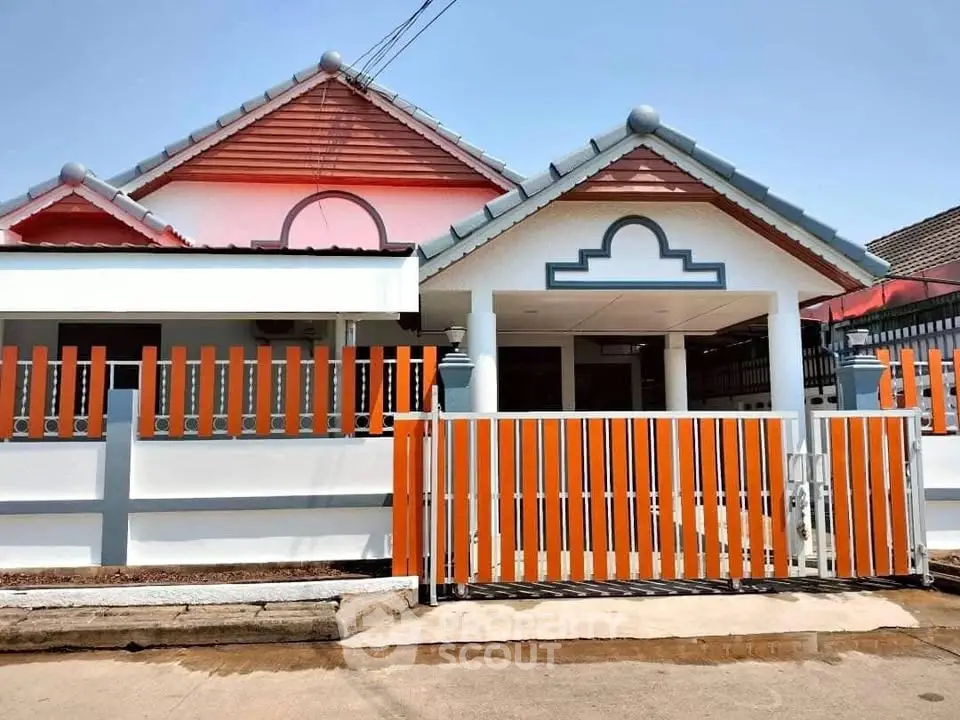 Charming single-story house with vibrant orange accents and a modern fence design.