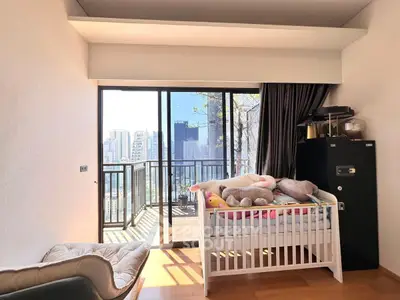 Bright bedroom with crib and balcony offering stunning city views