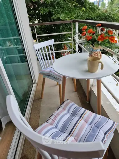 Charming balcony with cozy seating and lush greenery view, perfect for relaxation.