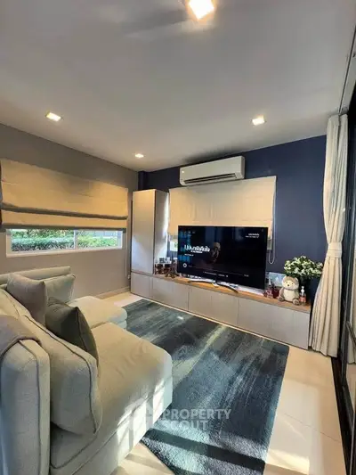 Stylish living room with modern decor and cozy ambiance, featuring a large TV and comfortable seating.