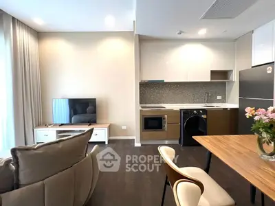 Modern open-layout living room with kitchen, featuring sleek appliances and stylish decor.