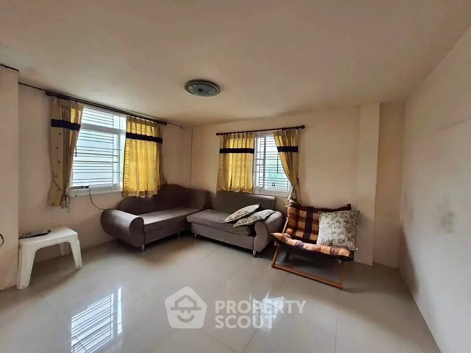 Spacious living room with cozy seating and natural light from large windows.