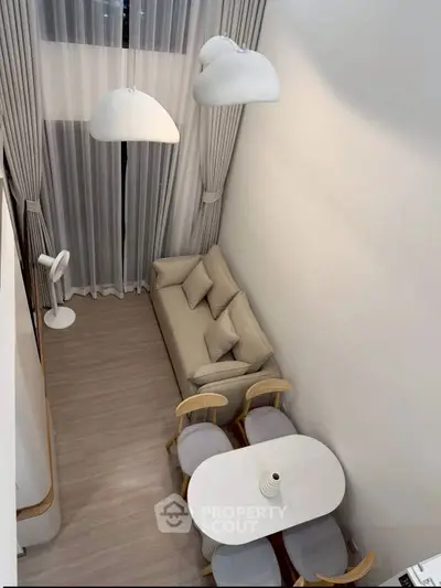 Modern living room with high ceiling, elegant lighting, and cozy seating area in a stylish apartment.