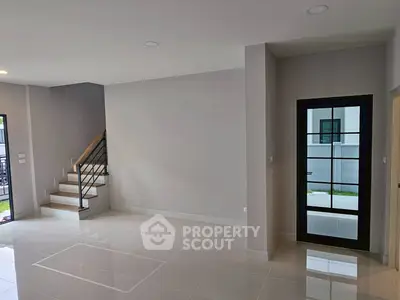 Spacious modern living room with sleek staircase and glass door, perfect for contemporary living.