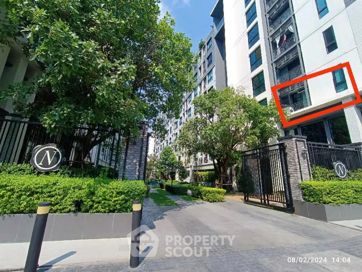 Modern apartment building with lush greenery and secure entrance gate