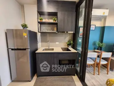 Modern compact kitchen with sleek cabinetry and stainless steel appliances in stylish apartment.