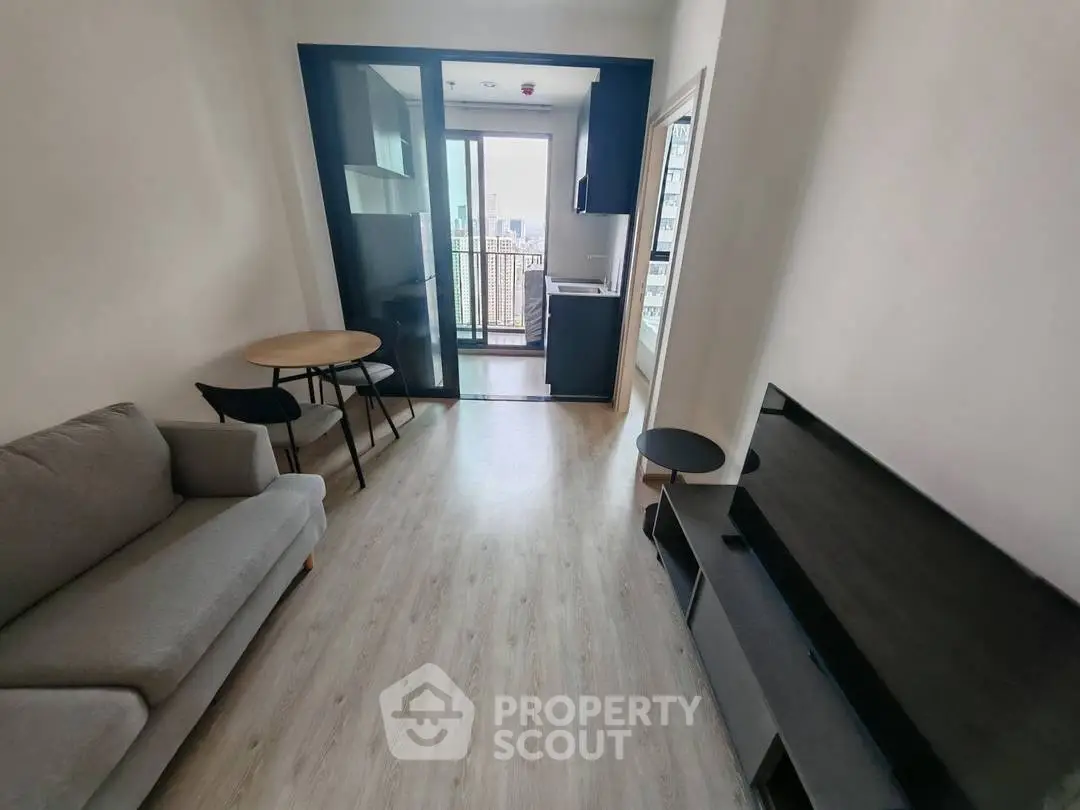 Modern living room with balcony access and sleek furniture in a compact apartment.