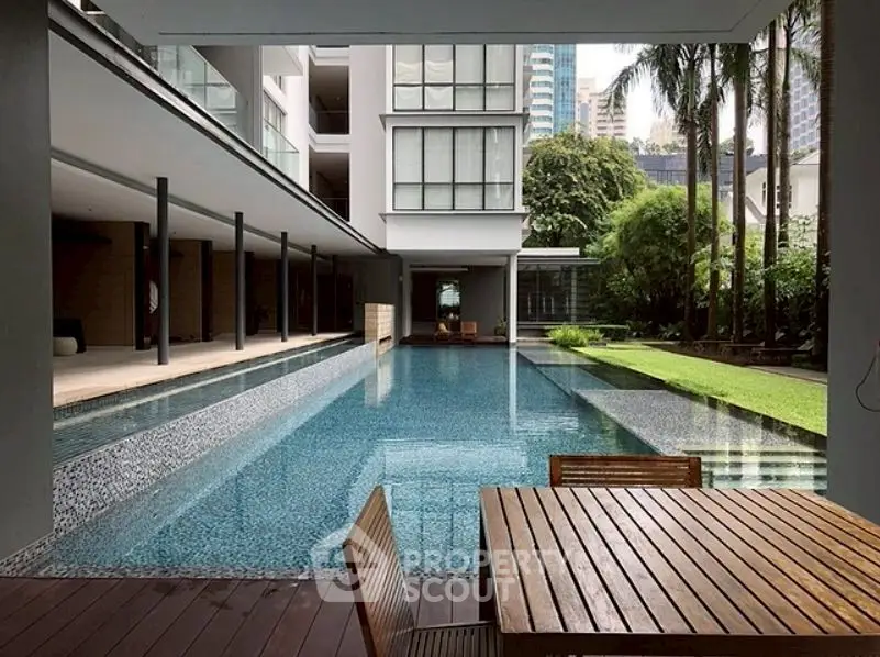 Luxurious modern apartment with poolside view and lush garden setting.