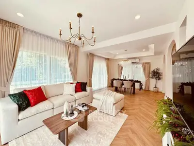 Elegant living room with chandelier, cozy seating, and large windows in a modern home.