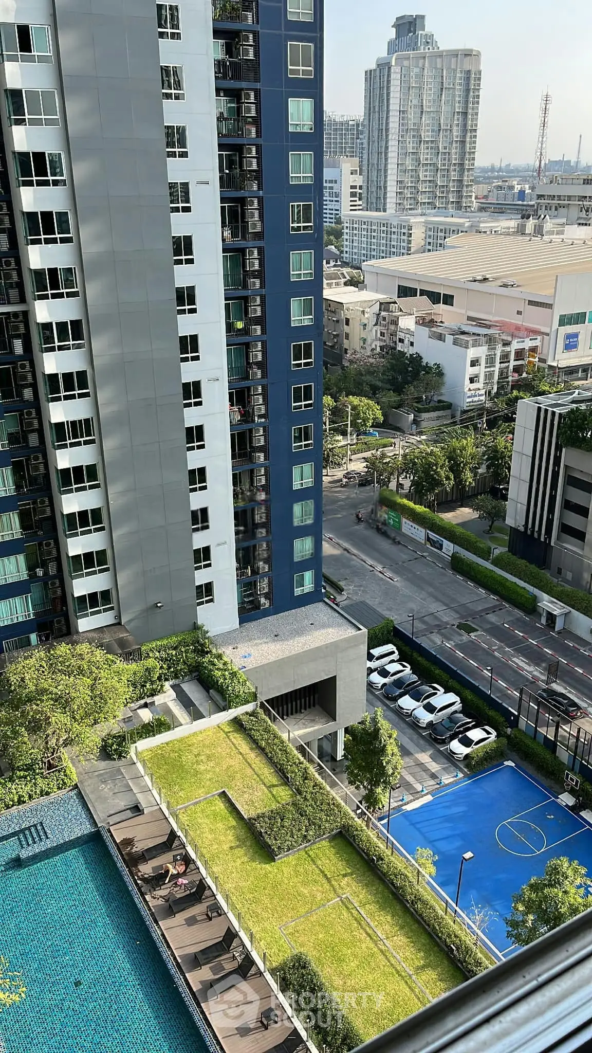 Stunning urban apartment view with pool, garden, and basketball court in a modern high-rise building.