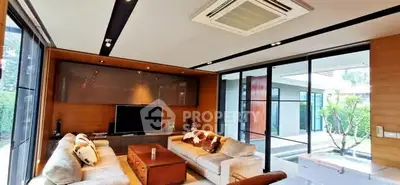 Modern living room with large windows and stylish furniture overlooking a garden.