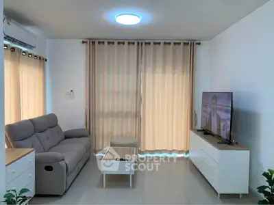 Modern living room with cozy sofa and flat-screen TV, perfect for relaxation.