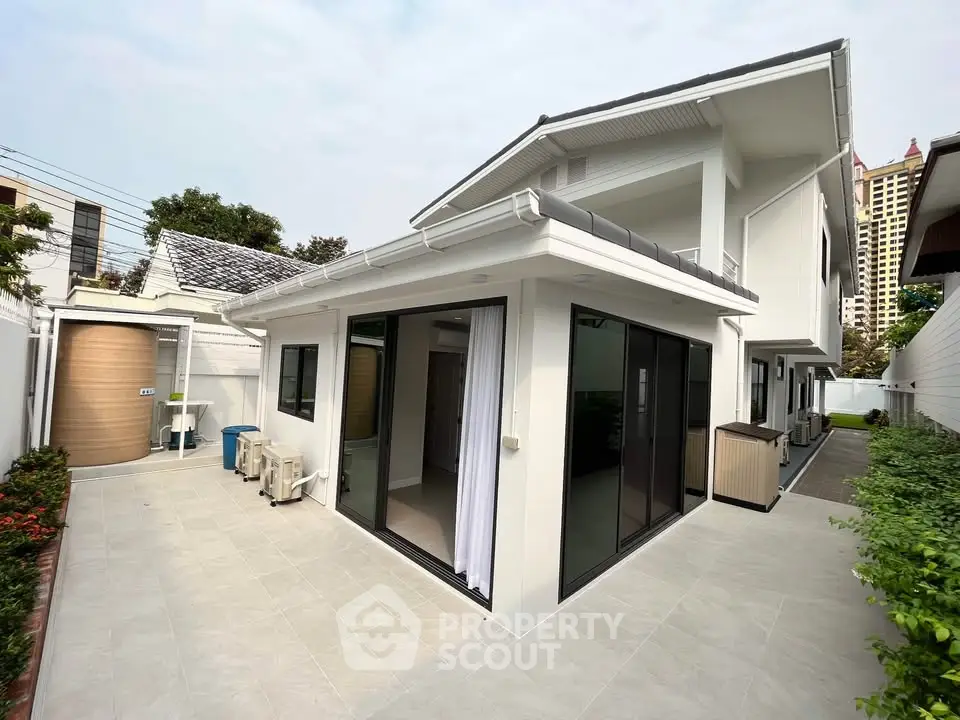 Modern white house with spacious patio and large windows, ideal for family living.