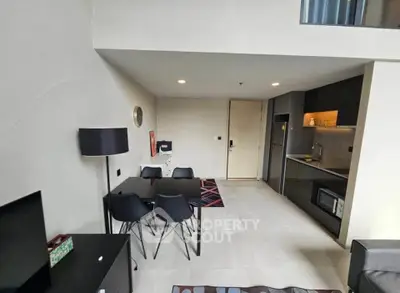 Modern open-plan living room with sleek kitchen and dining area in stylish apartment.