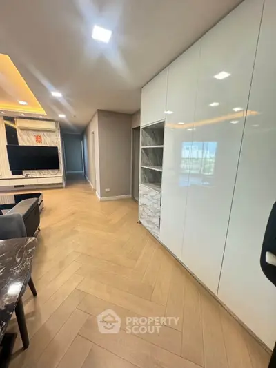 Modern living room with sleek design and wooden flooring, featuring a wall-mounted TV and stylish cabinetry.