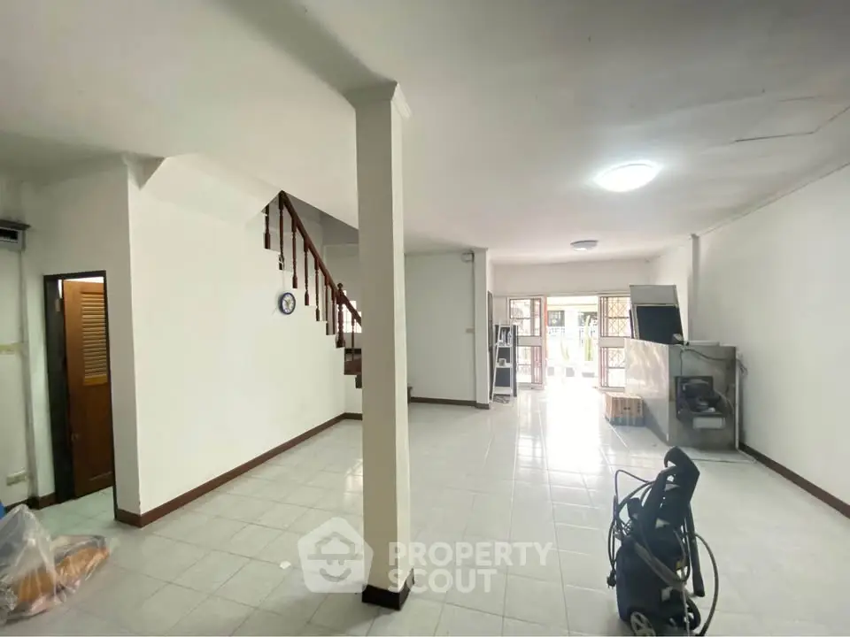 Spacious open-plan living area with staircase and large windows for natural light.