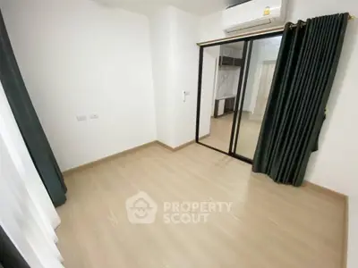 Spacious empty room with wooden flooring and large mirrored closet doors, perfect for customization.