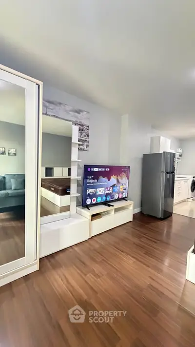 Modern living room with sleek furniture and appliances, featuring a large TV and stylish decor.